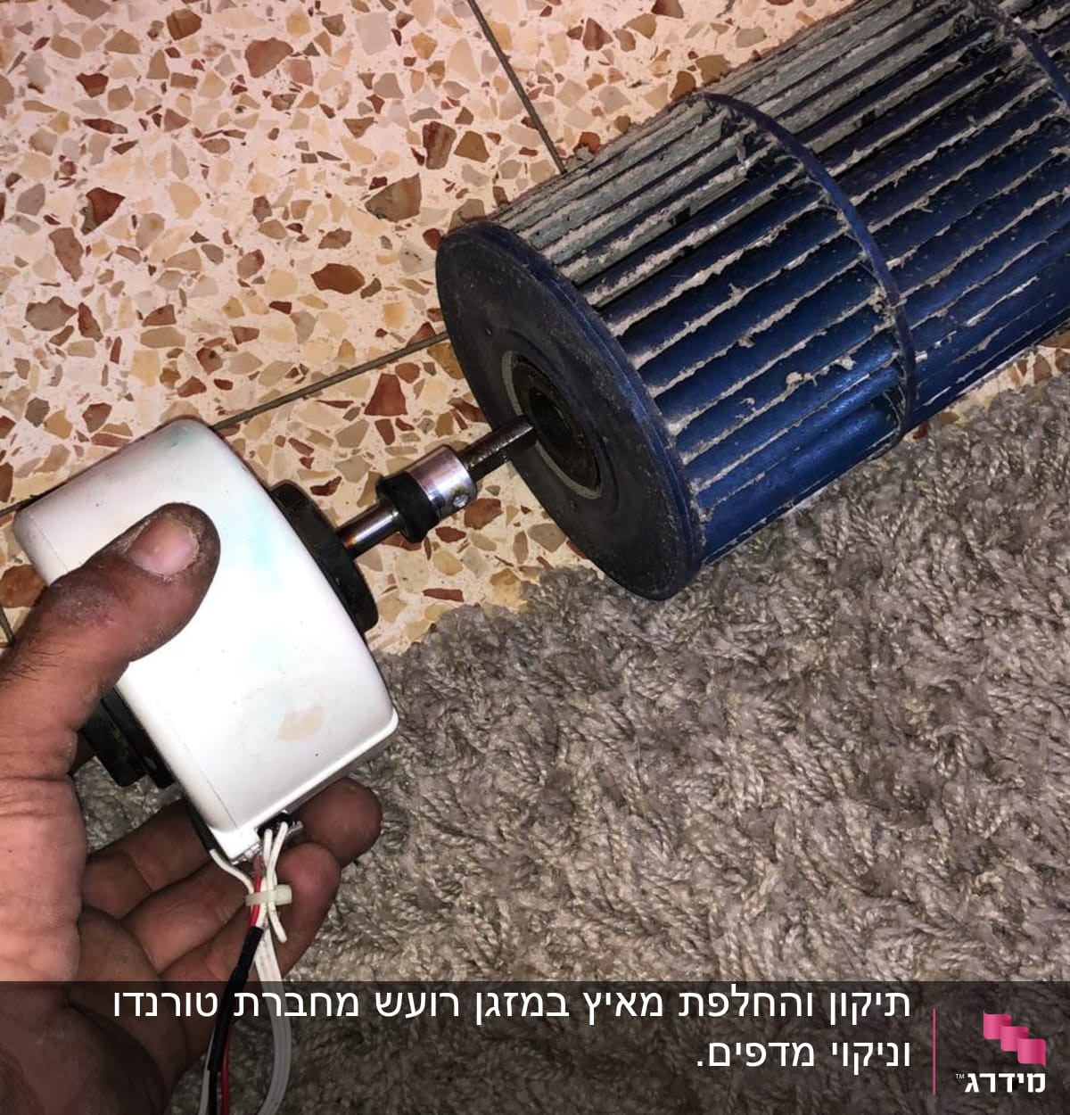 יד מחזיקה מנוע קטן ליד מאוורר של מזגן